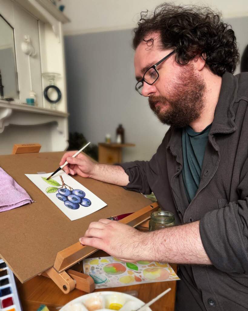 Seamus working at his drawing desk in the Shimmus Studios workspace.
